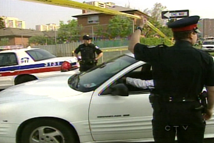 Toronto police officers speak with people outside C.W. Jefferys Collegiate Institute.