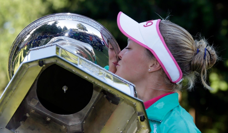 After being prompted by organizers, Brooke Henderson, of Canada, plants a kiss on the championship trophy after winning the Women's PGA Championship golf tournament at Sahalee Country Club on Sunday, June 12, 2016, in Sammamish, Wash. (AP Photo/Elaine Thompson)