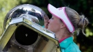 After being prompted by organizers, Brooke Henderson, of Canada, plants a kiss on the championship trophy after winning the Women's PGA Championship golf tournament at Sahalee Country Club on Sunday, June 12, 2016, in Sammamish, Wash. (AP Photo/Elaine Thompson)