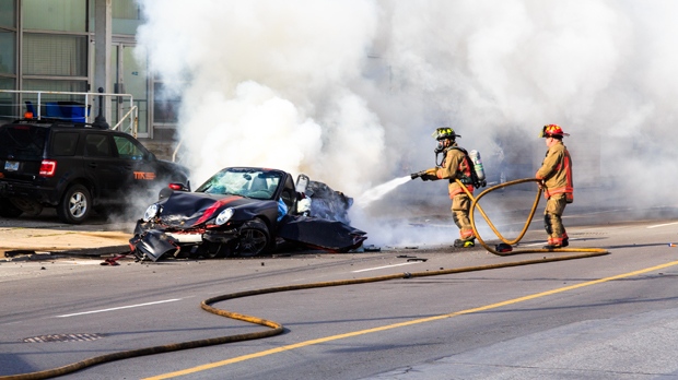 Firefighters douse flames on a Porsche that crashed on Queen's Quay in Toronto on Saturday, July 2, 2016. (Dave Bottoms)