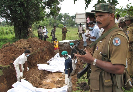 A police officer stands guard as Red Cross workers bury the bodies of Tamil rebel fighters in a cemetery in Vavuniya, about 210 kilometres northeast of Colombo, Sri Lanka, Wednesday, Jan. 14, 2009. (AP / Sanath Priyantha)