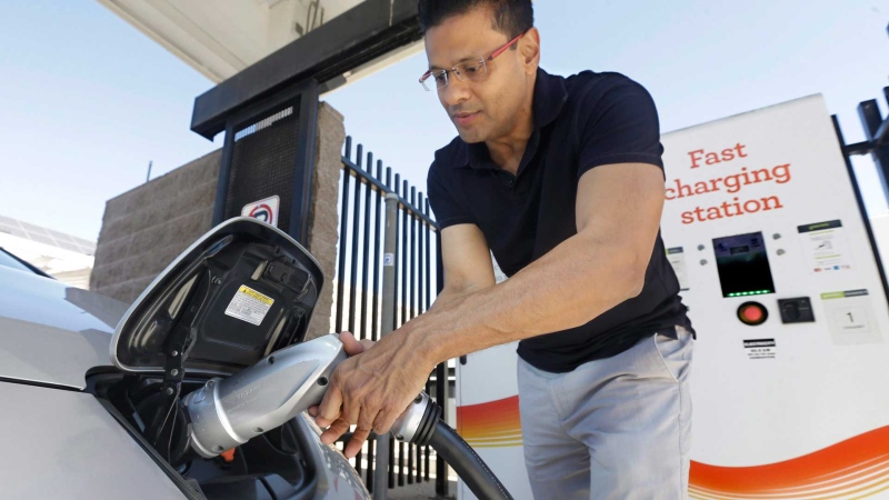 In this photo taken Thursday, Sept. 17, 2015, Darshan Brahmbhatt, plugs a charger into his electric vehicle at the Sacramento Municipal Utility District charging station in Sacramento, Calif. (AP Photo/Rich Pedroncelli)
