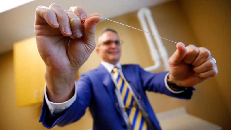 Dr. Wayne Aldredge, president of the American Academy of Periodontology, holds a piece of dental floss at his office in Holmdel, N.J. (AP / Julio Cortez)