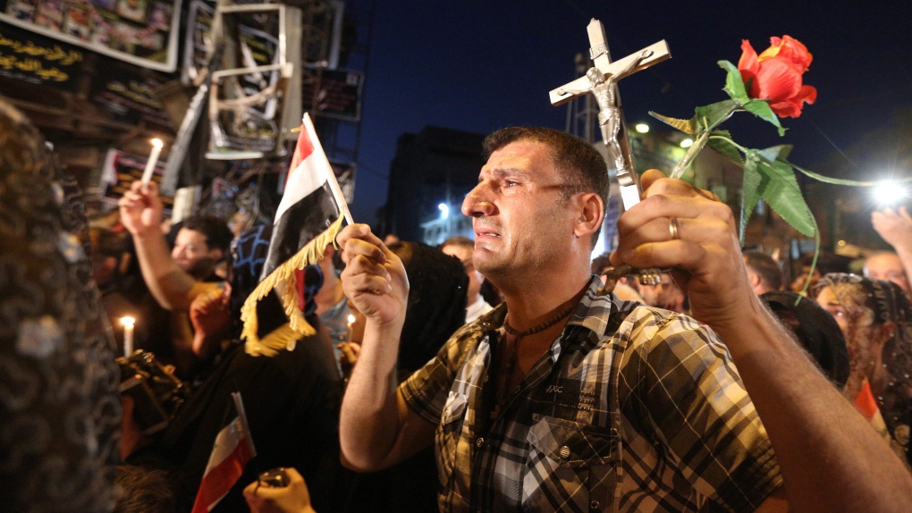 Iraqi Christians pray as they hold national flags 
