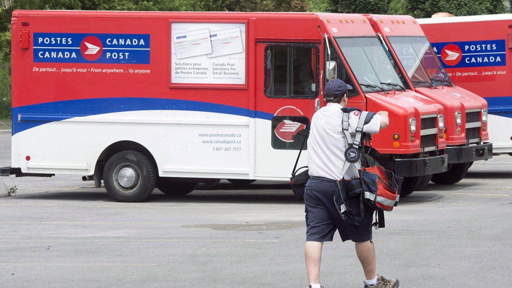 A postal worker walks past Canada Post trucks