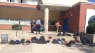 Police officers and teachers remove students' backpacks from Lakeshore Collegiate and place them outside on Sept. 9, 2016. (Cam Woolley/CP24)