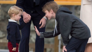 Flower boy Daniel Brachman tries to give Prince George a high five as the Duke and Duchess of Cambridge look on prior to the Royal family boarding a float plane to depart Victoria, B.C. Saturday, Oct. 1, 2016. THE CANADIAN PRESS/Jonathan Hayward