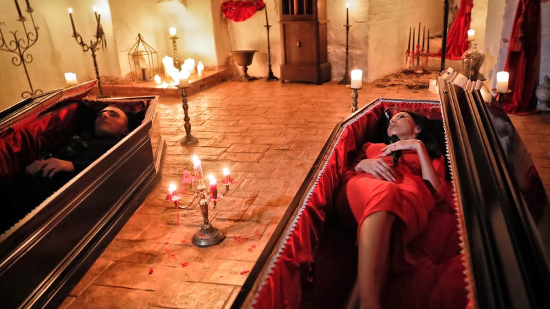 Tami Varma, right, and her brother Robin, the grandchildren of Devendra Varma, a scholar of English gothic tales and an expert in vampire lore, pose in coffins at the Bran Castle, in Bran, Romania, Monday, Oct. 31, 2016. A Canadian brother and sister are passing Halloween night curled up in red velvet coffins in the Transylvanian castle that inspired the Dracula legend, the first time in 70 years anyone has spent the night in the gothic fortress, after they bested 88,000 people who entered a competition hosted by Airbnb to get the chance to dine and sleep at the castle in Romania. A portrait of medieval prince Vlad the Impaler is placed on the wall. (Vadim Ghirda/AP Photo)