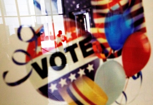In this Nov. 1, 2016, photo, a voter is reflected in the glass frame of a poster while leaving a polling site during early voting ahead of next week's election in Atlanta. (AP Photo/David Goldman)