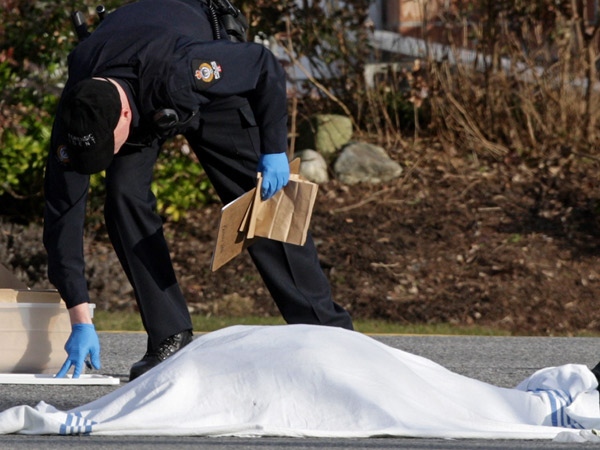 A police officer works near a body covered by a blanket following a suspected shooting in Vancouver, B.C., on Tuesday, Feb. 17, 2009. (Darryl Dyck / THE CANADIAN PRESS)