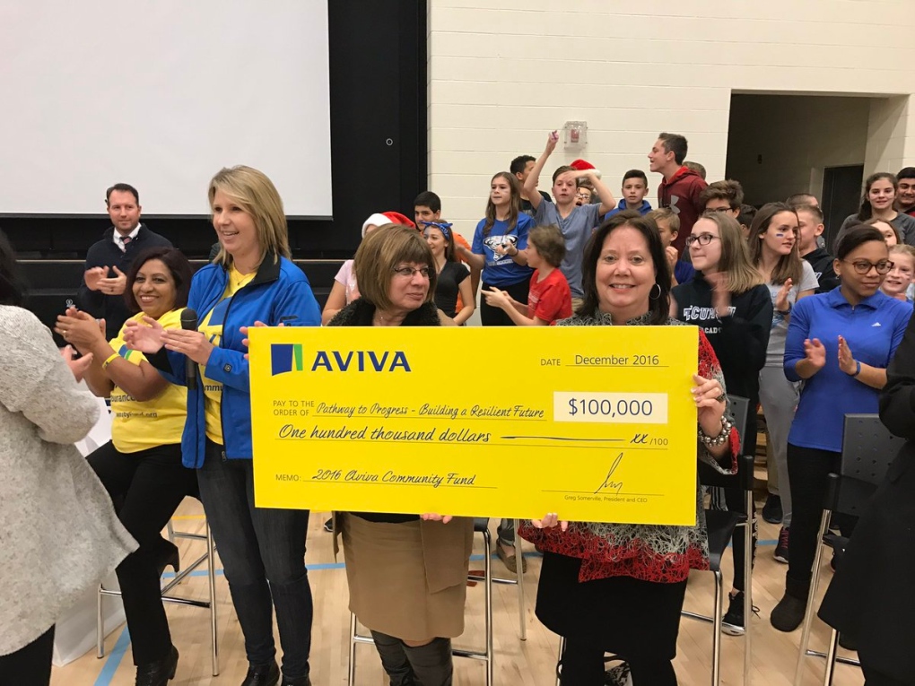 Board administrators hold a cheque for $100,000