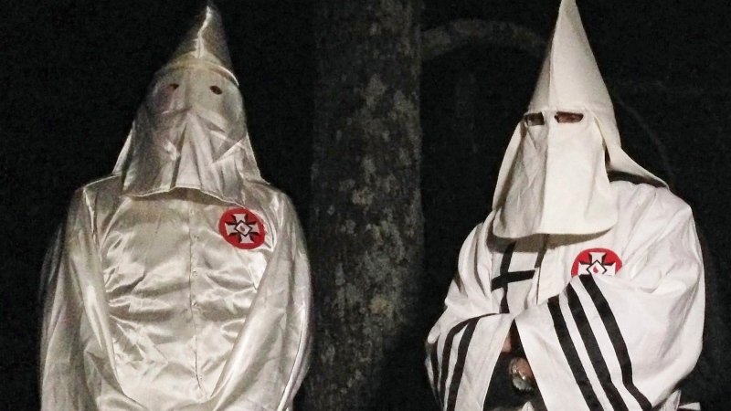 Two masked Ku Klux Klansmen stand on a muddy dirt road during an interview near Pelham, N.C. on Friday, Dec. 2, 2016 . (AP / Jay Reeves)
