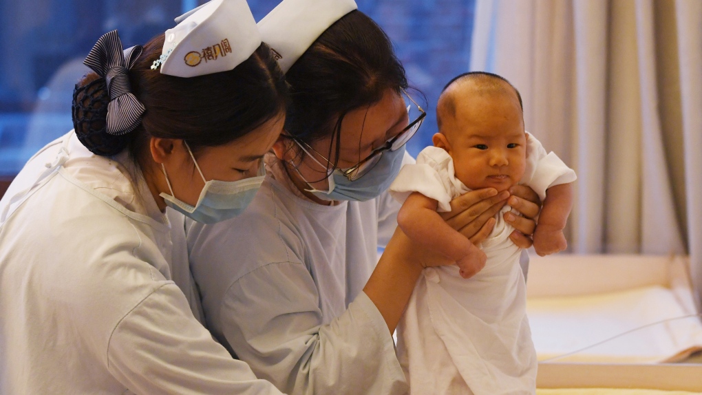 Nurses hold up a baby in China (Greg Baker / AFP)
