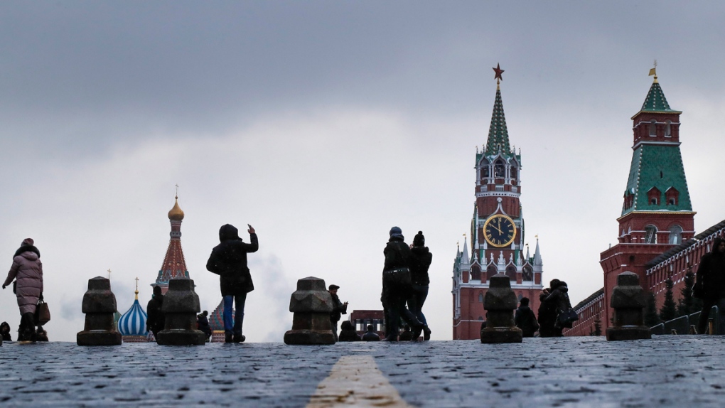 Tourists take pictures of the Kremlin, right