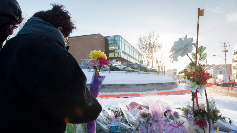 A woman places flowers near a mosque where a Sunday night shooting left six people dead, Monday, January 30, 2017 in Quebec City. THE CANADIAN PRESS/Paul Chiasson
