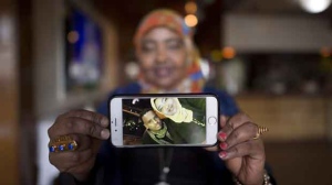 Saciido Shaie, founder and President of the Umma Project holds a picture of herself and close friend Mohamed Badal at a Somali restaurant in Minneapolis, Minn., on Thursday, Feb. 16, 2017. Badal left the United States last week and trekked through the snow covered boarder to get himself into Canada. (Source: Jonathan Hayward/The Canadian Press)
