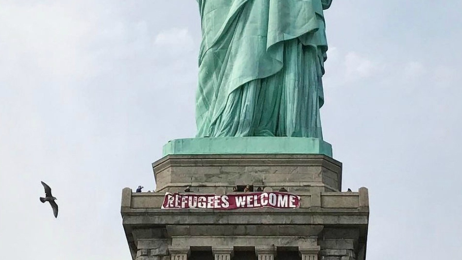 Refugees welcome banner on statue of liberty