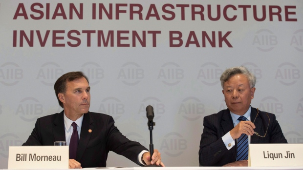 Canadian Minister of Finance Bill Morneau adjusts a microphone as he sits with the President of the Asian Infrastructure Investment Bank Jin Liqun during a news conference at the Asian Infrastructure Investment Bank in Beijing, August 31, 2016. (Adrian Wyld / The Canadian Press)