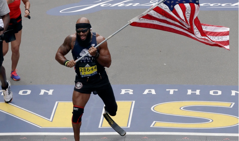 Jose Sanchez, of San Antonio, carries the United States flag across the finish line in the 121st Boston Marathon on Monday, April 17, 2017. (AP / Charles Krupa)