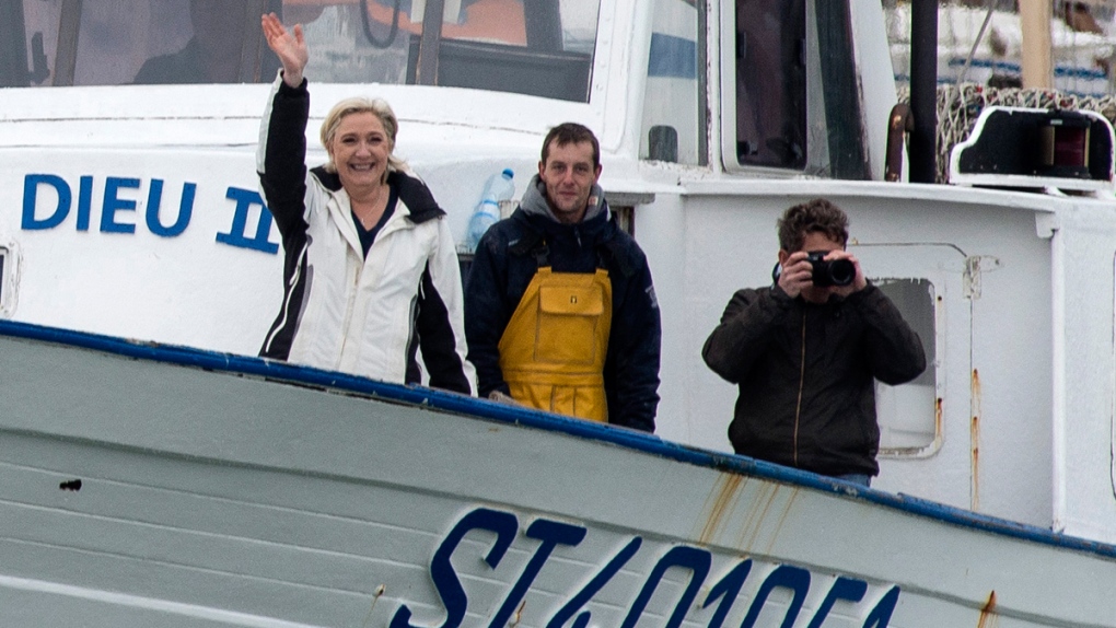 Marine le Pen, left, waves from a fishing trawler