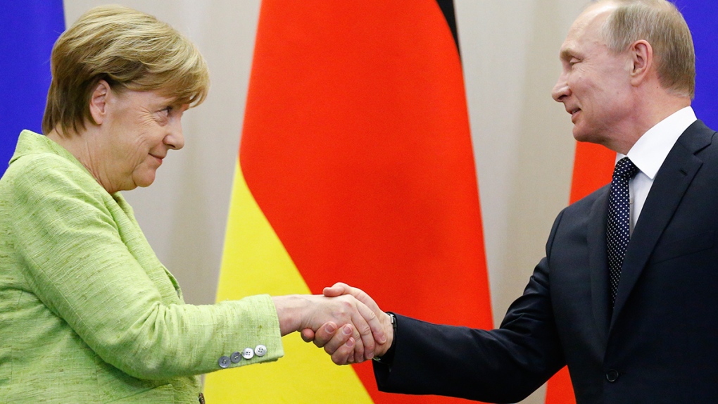 Vladimir Putin shakes hands with Angela Merkel