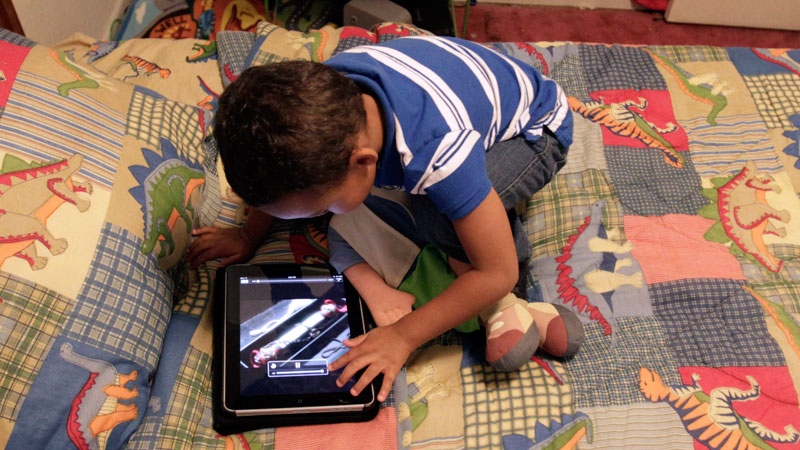 A preschooler plays with an iPad