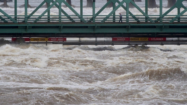 A pedestrian walks across the Chaudiere bridge as high waters on the Ottawa river pass just under Saturday May 6, 2017 in Ottawa. Parts of the region are seeing flood due to high water levels and heavy rains.THE CANADIAN PRESS/Adrian Wyld