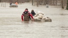 Residents are seen in waist high water transporting sandbags in a boat down a flooded street. 