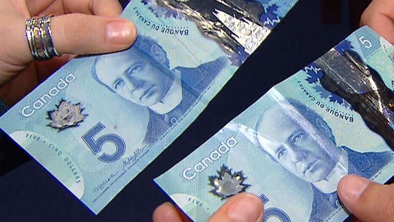 Penny Daflos (left) and Bank of Canada analyst Farid Salji hold up real and counterfeit $5 bills.