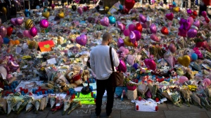 A man stands next to flowers for the victims of Monday's bombing at St. Ann's Square in central Manchester, England, Friday, May 26 2017. British police investigating the Manchester Arena bombing arrested a ninth man while continuing to search addresses associated with the bomber. (AP Photo / Emilio Morenatti) 