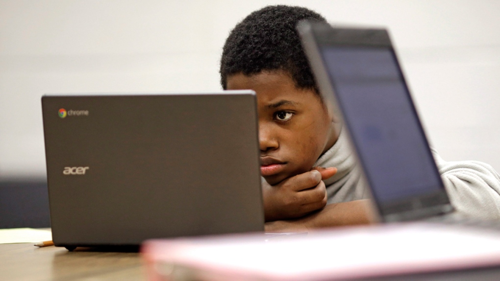 A boy reads on a laptop computer