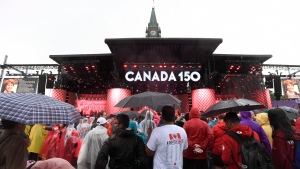 People use umbrellas to shelter themselves from the rain during Canada 150 celebrations in Ottawa on Saturday, July 1, 2017. (Justin Tang / THE CANADIAN PRESS)