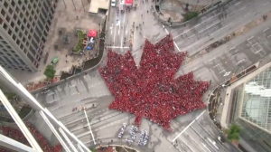 The group, dressed in the national colours of red and white, gathered on Portage Avenue and Main Street to form the giant maple leaf.