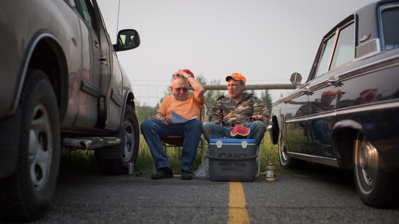 Garth Lee, left, and his son Floyd Lee, both evacuated from their homes in 108 Mile Ranch, sit in the parking lot outside a curling club being used as an evacuation centre in 100 Mile House, B.C., on Saturday July 8, 2017. THE CANADIAN PRESS/Darryl Dyck