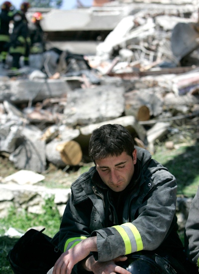 A firefighter sits by the site of a four-story building collapse, in L'Aquila, central Italy, on Monday, April 6, 2009. (AP / Pier Paolo Cito)