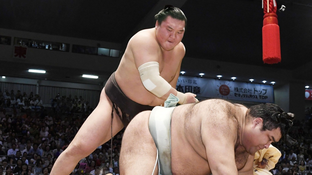 Hakuho, left, topples champion Takayasu