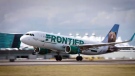 A Frontier Airlines plane is seen taking off from a runway.