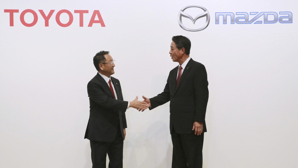 Akio Toyoda, left, and Masamichi Kogai shake hands