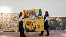 Sotheby's employees carry U.S. artist Jean-Michel Basquiat's painting 'Orange Sports Figure' (1982), during a press preview for Sotheby's 'Impressionist and Modern Art' sale in London on Feb, 1, 2012. JUSTIN TALLIS / AFP