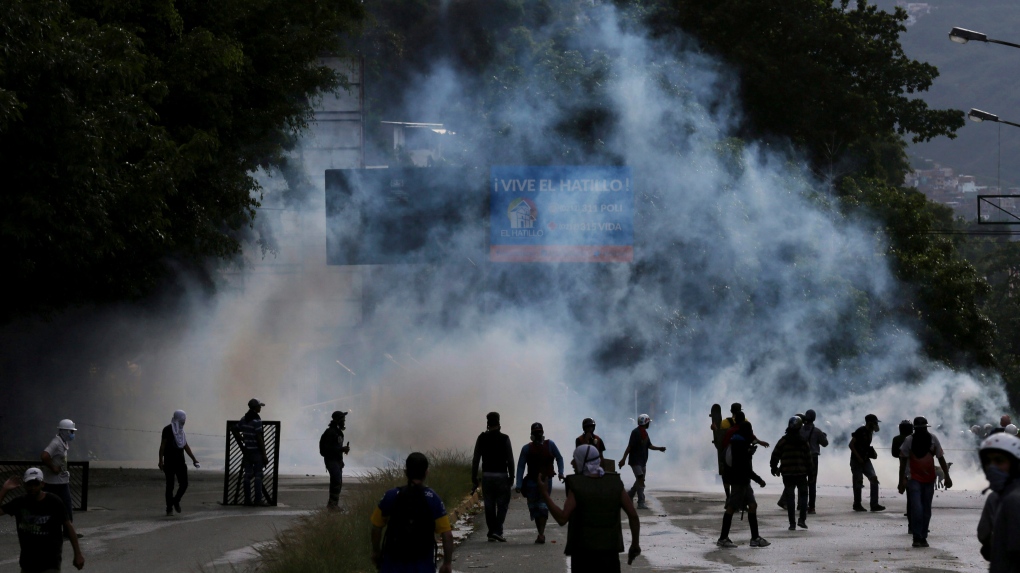 Demonstrators walk amid tear gas in El Hatillo