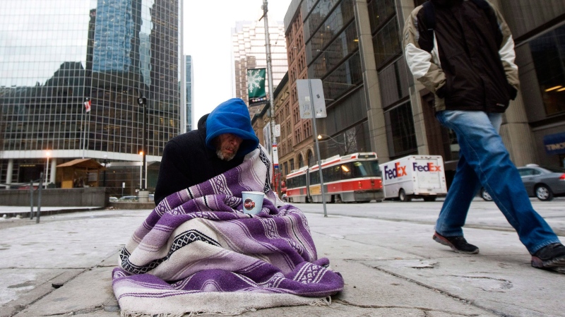 In this file photo, a person experiencing homelessness panhandles for money in Toronto on Monday, Dec. 13, 2010. (The Canadian Press / Nathan Denette) 