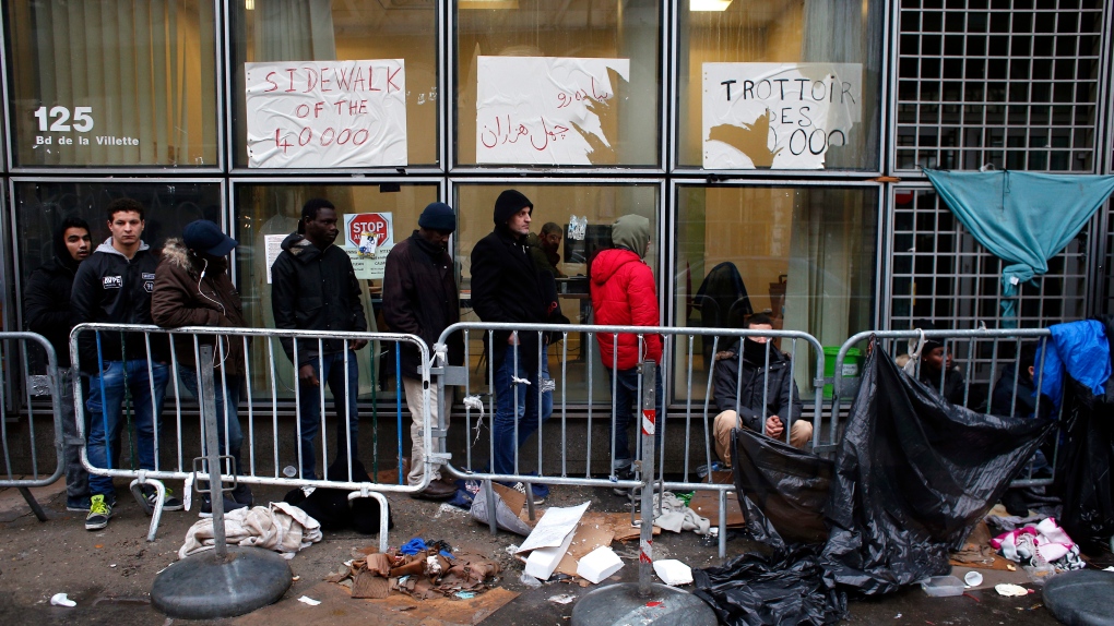 Migrants queue outside a facility in Paris
