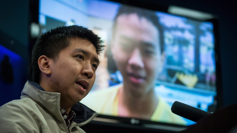 Wilfred Wong, left, speaks about his brother Alfred Wong, 15, seen on a television, who was an innocent victim of an alleged gang shooting, during a Vancouver Police news conference in Vancouver, B.C., on Monday January 22, 2018. THE CANADIAN PRESS/Darryl Dyck
