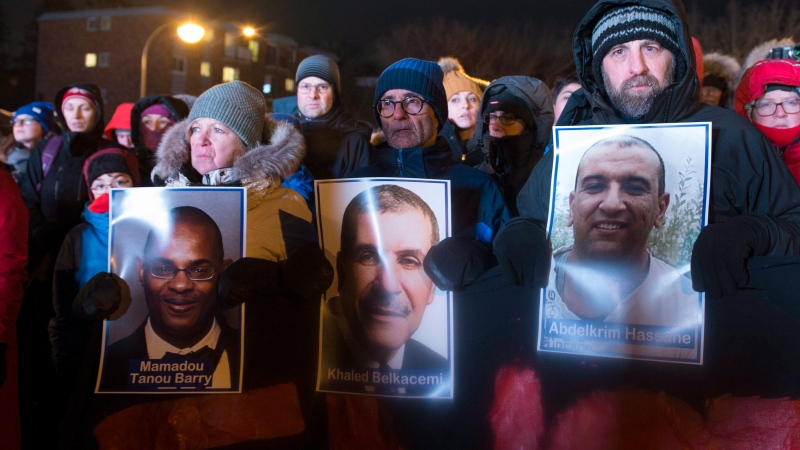 People hold pictures of the victims at a vigil to commemorate the one-year anniversary of the Quebec City mosque shooting, in Quebec City, Monday, Jan. 29, 2018. THE CANADIAN PRESS/Jacques Boissinot