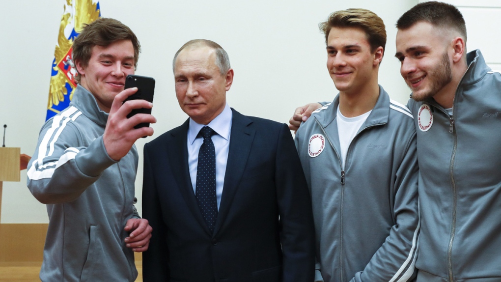 Vladimir Putin poses with Russian athletes