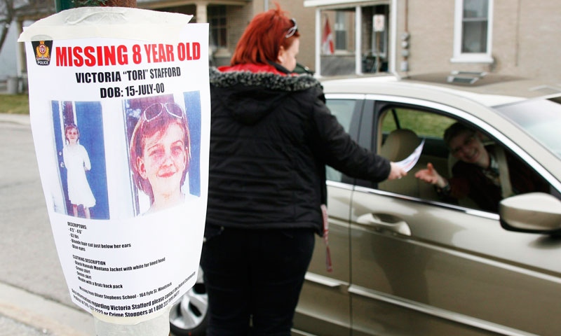 Tiffany Ackers hands out a poster for missing Victoria 'Tori' Stafford, 8, on a street corner in Woodstock, Ont. on Friday April 10, 2009. THE CANADIAN PRESS/Dave Chidley