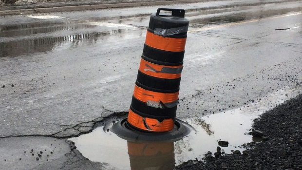 A pilon alerts motorists to a large pothole on Colonel By Drive in Ottawa on Wednesday, Feb. 21, 2018. 