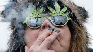 The Peace Tower is reflected in the sunglasses of a woman smoking a joint during a marijuana rally on Parliament HIll in Ottawa on April 20, 2013. (Justin Tang / THE CANADIAN PRESS)