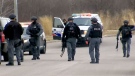Heavily armed police officers search an area off the side of Highway 401 in Ajax after three robbery suspects abandoned a vehicle and fled into a wooded area on March 12, 2018.