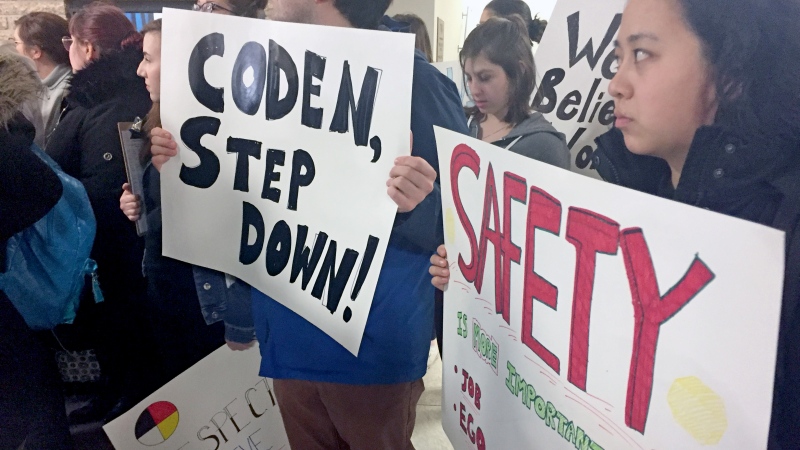Students at the University of Saskatchewan hold up signs calling for Coden Nikbakht to step aside Friday, March 23, 2018, one day after Nikbakht was elected president of the undergraduate students' union. (Ashley Field/CTV Saskatoon)